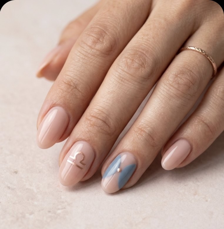 Minimal Libra manicure with soft rosy nude oval nails, fine rose gold mirrored curves, Libra glyph and dusty blue accent.