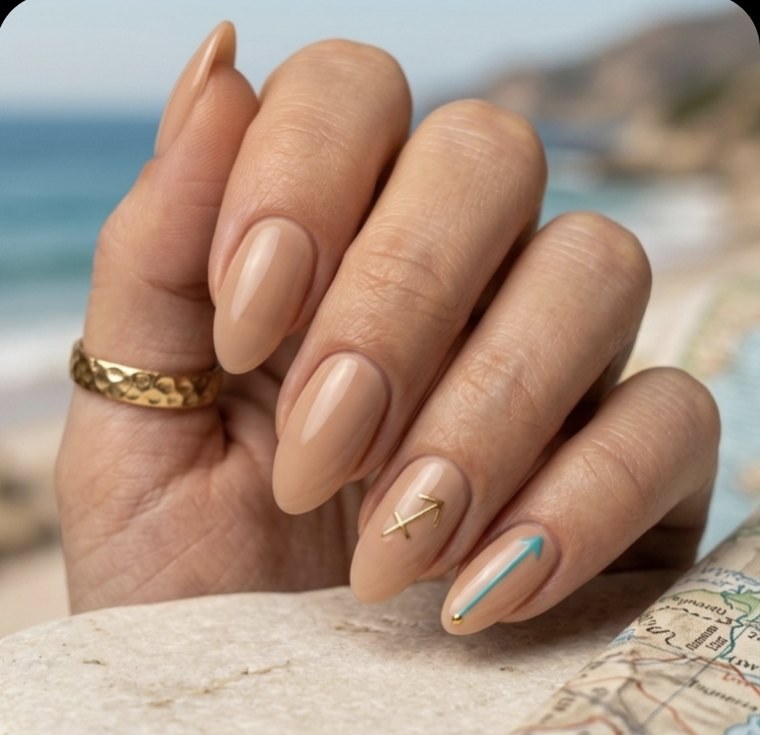 Minimal Sagittarius manicure with warm sandy almond nails, sunlit gold arrow accent, Sagittarius glyph and turquoise details.